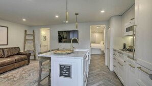 Una cocina moderna con armarios blancos, horno integrado y encimera con lavabo.