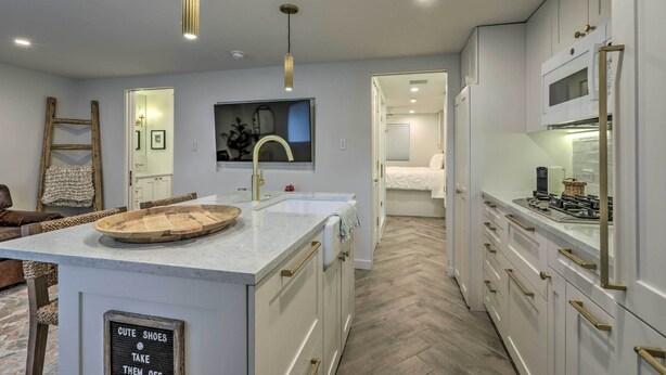 Una cocina moderna con armarios blancos, una isla grande y un piso con patrón de espiga.