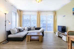A living room with a sectional sofa, a coffee table, a TV on a stand, and a floor lamp.