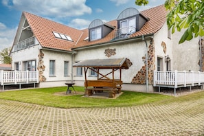 Une maison avec une façade en pierre, une terrasse en bois et un espace extérieur aménagé avec des sièges.