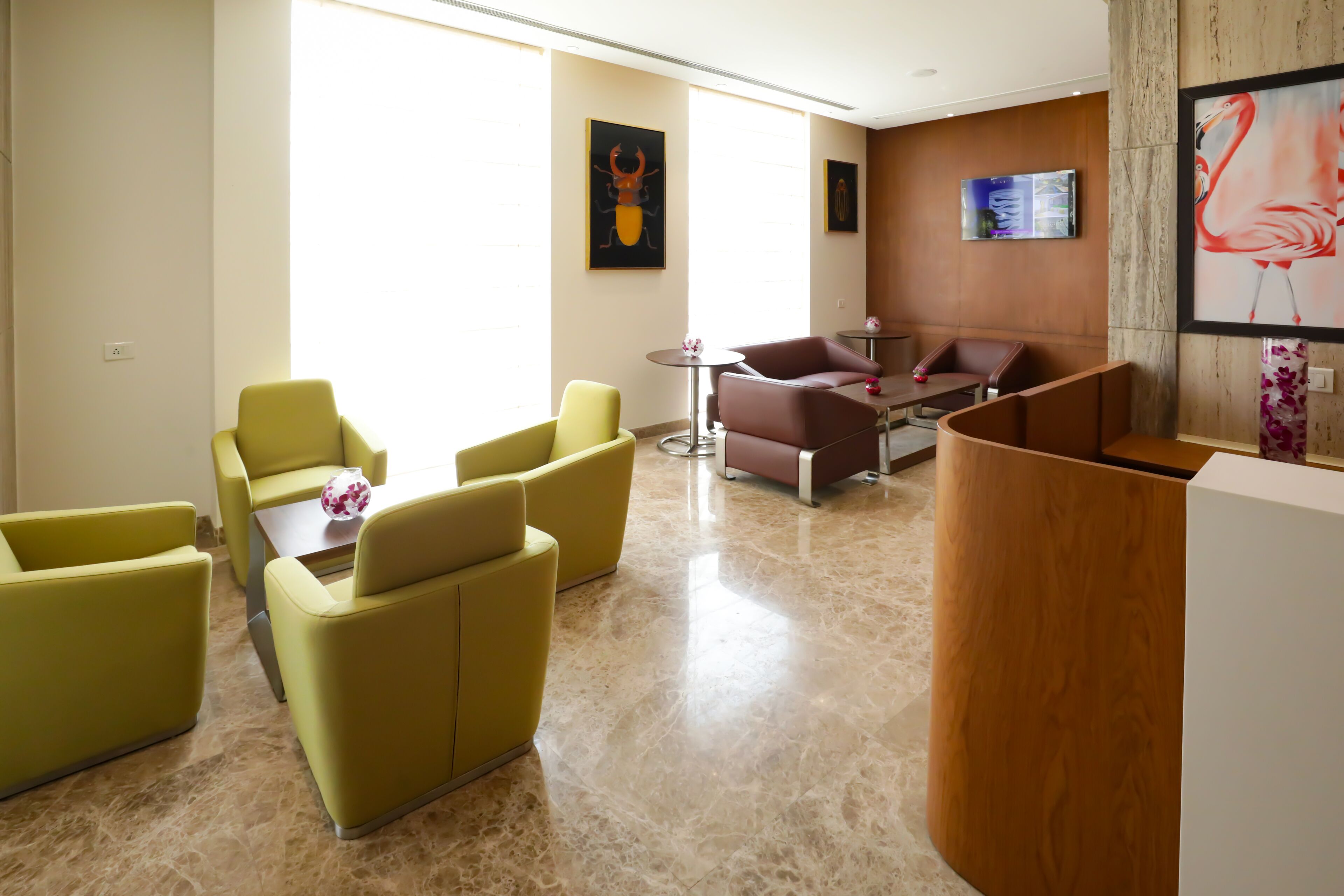 Un moderno vestíbulo de hotel con asientos amarillos y marrones, una recepción y obras de arte en las paredes.