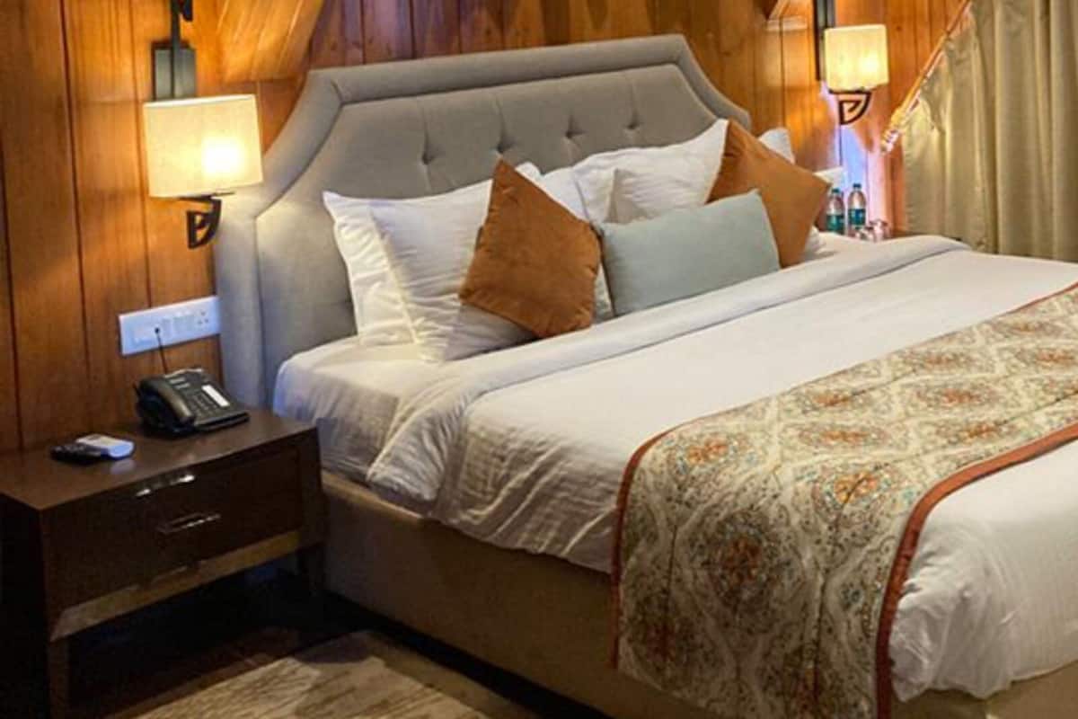 A hotel room with a large bed, a bedside table with a phone, and a lamp.