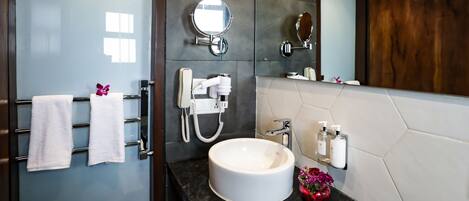 A modern bathroom with a large mirror, a round sink, and a towel rack with white towels.