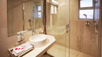 A modern bathroom with a glass-enclosed shower, a large mirror, and a vanity with a sink and toiletries.