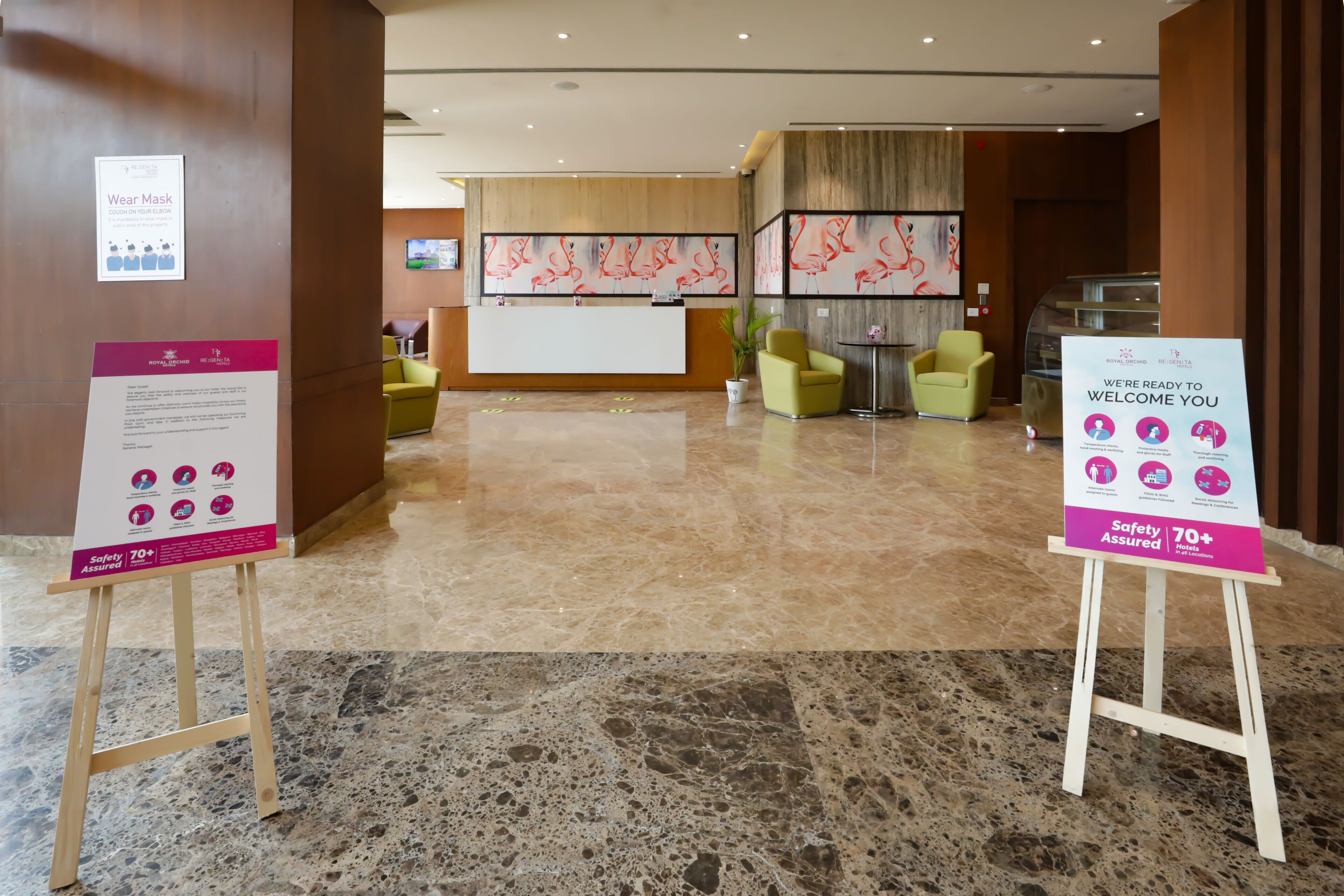 A hotel lobby with a reception desk, seating area, and informational posters.