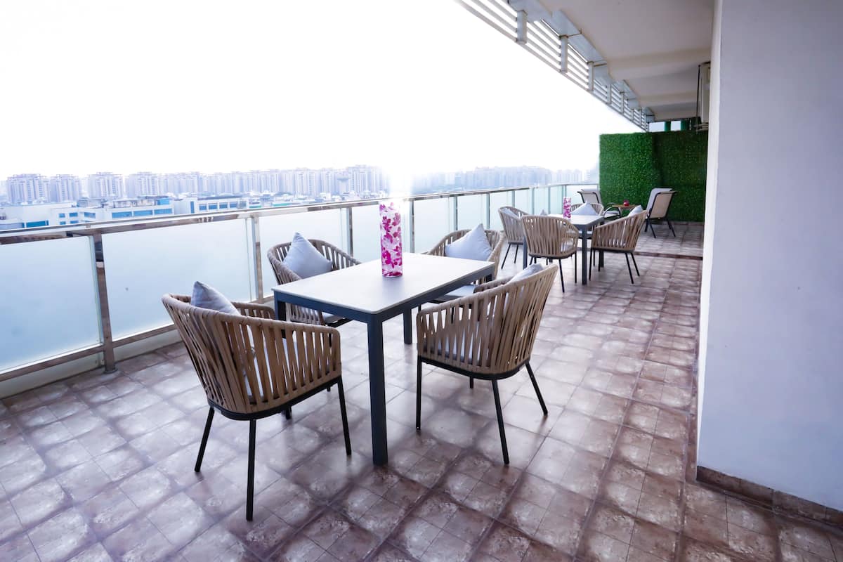 A balcony with a table and chairs, overlooking a cityscape.