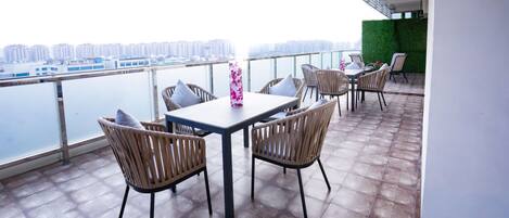 A balcony with a table and chairs, overlooking a cityscape.