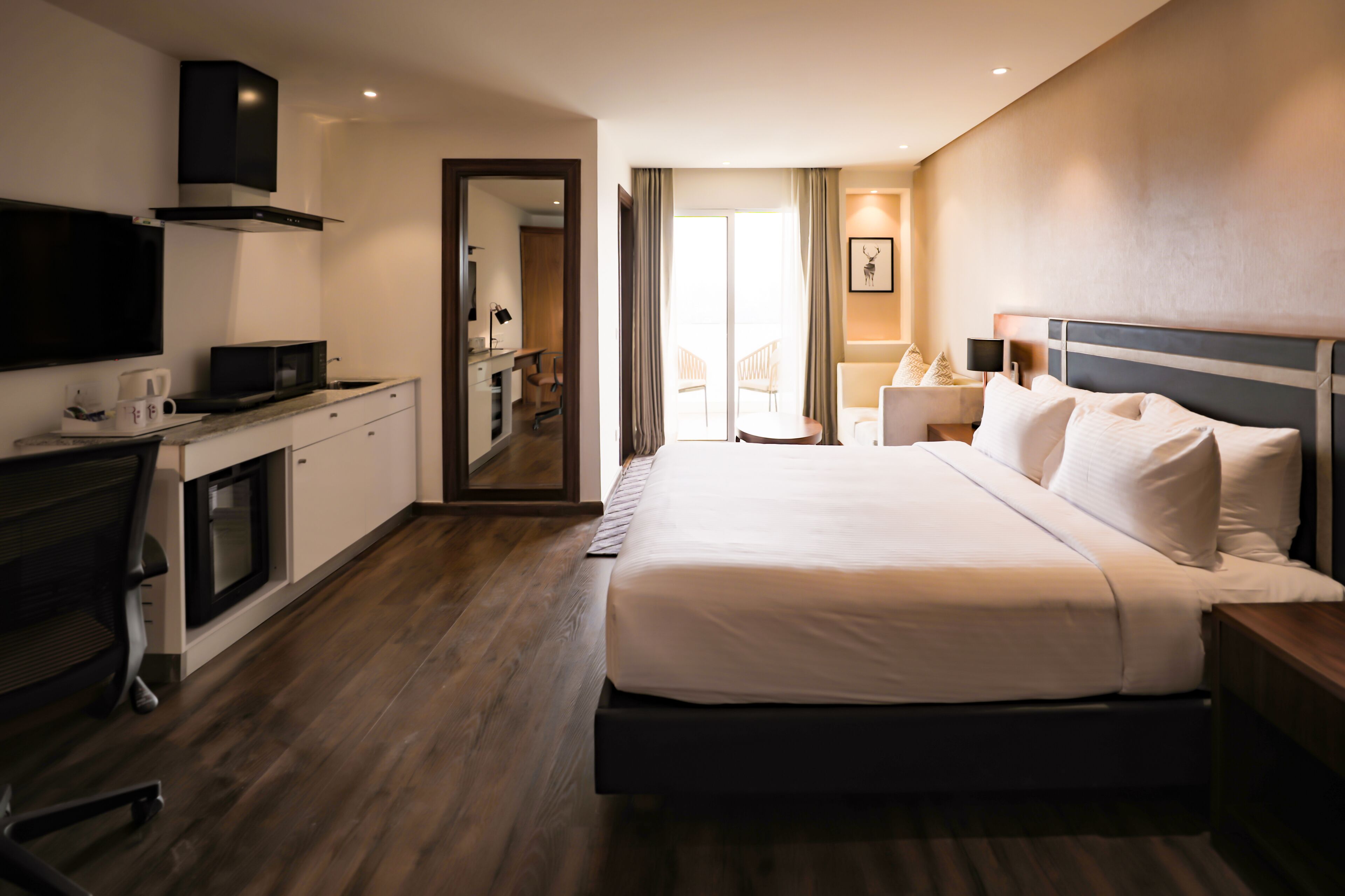 A hotel room with a bed, a desk with a computer, a microwave, and a TV.