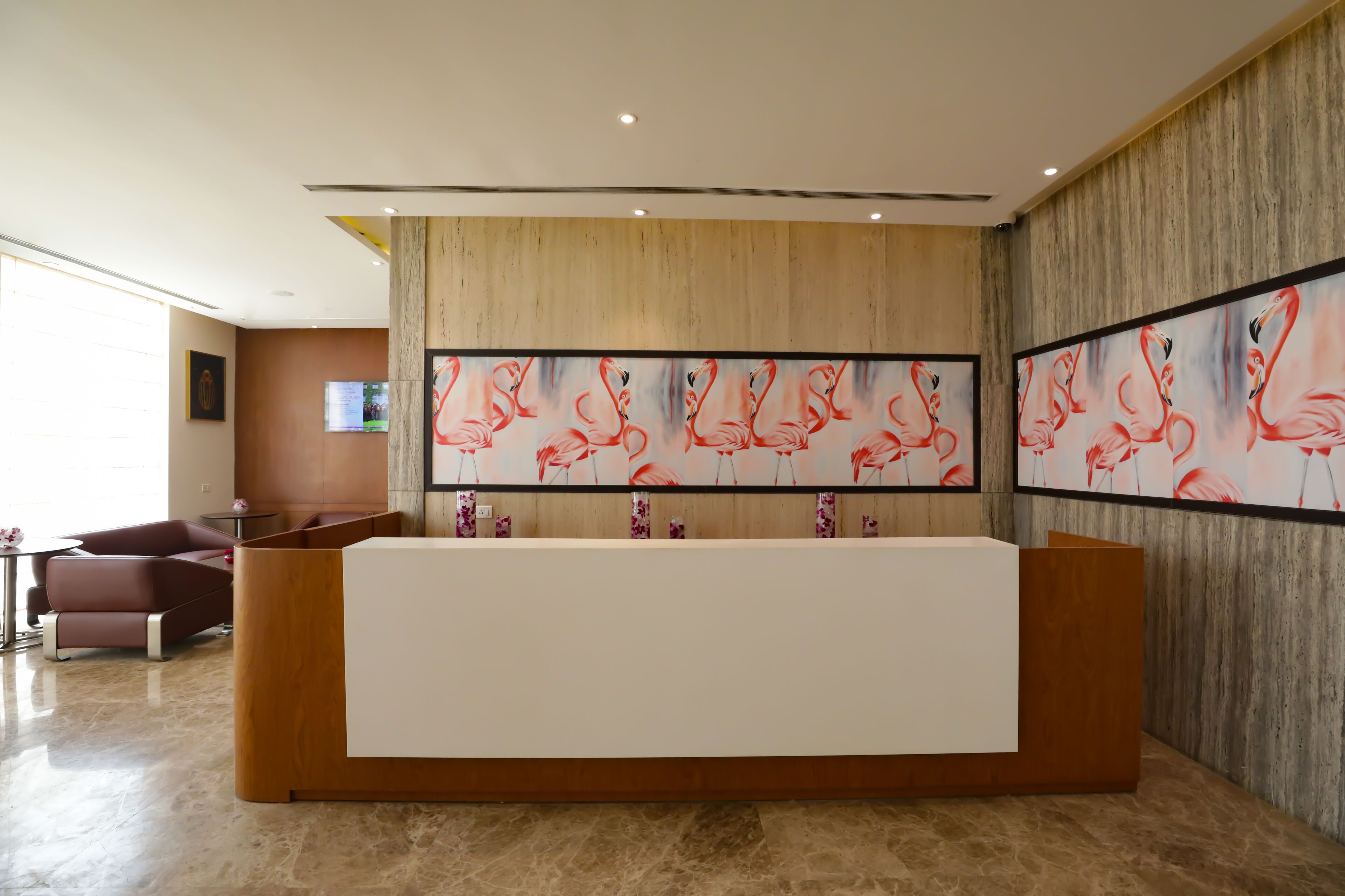 A reception area with a wooden reception desk, two framed wall art pieces, and a brown wall.