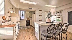 Een moderne keuken met een centraal eiland, houten vloeren en een eethoek met metalen stoelen.