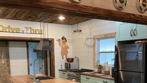 A modern kitchen with a central island, bar stools, a refrigerator, and a stove. - RUSTIC GLAM (Mentone)