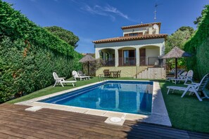 A two-story house with a swimming pool, outdoor furniture, and a well-maintained garden.