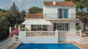 Une maison à deux étages avec une piscine, un balcon et un jardin.