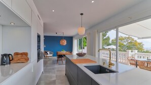 Une cuisine moderne dotée d’un îlot central, d’un coin repas avec une table et des chaises, et offrant une vue sur l’extérieur.