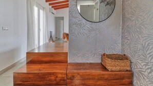 Un couloir doté d’un plancher en bois, d’un miroir et d’un papier peint à motifs.
