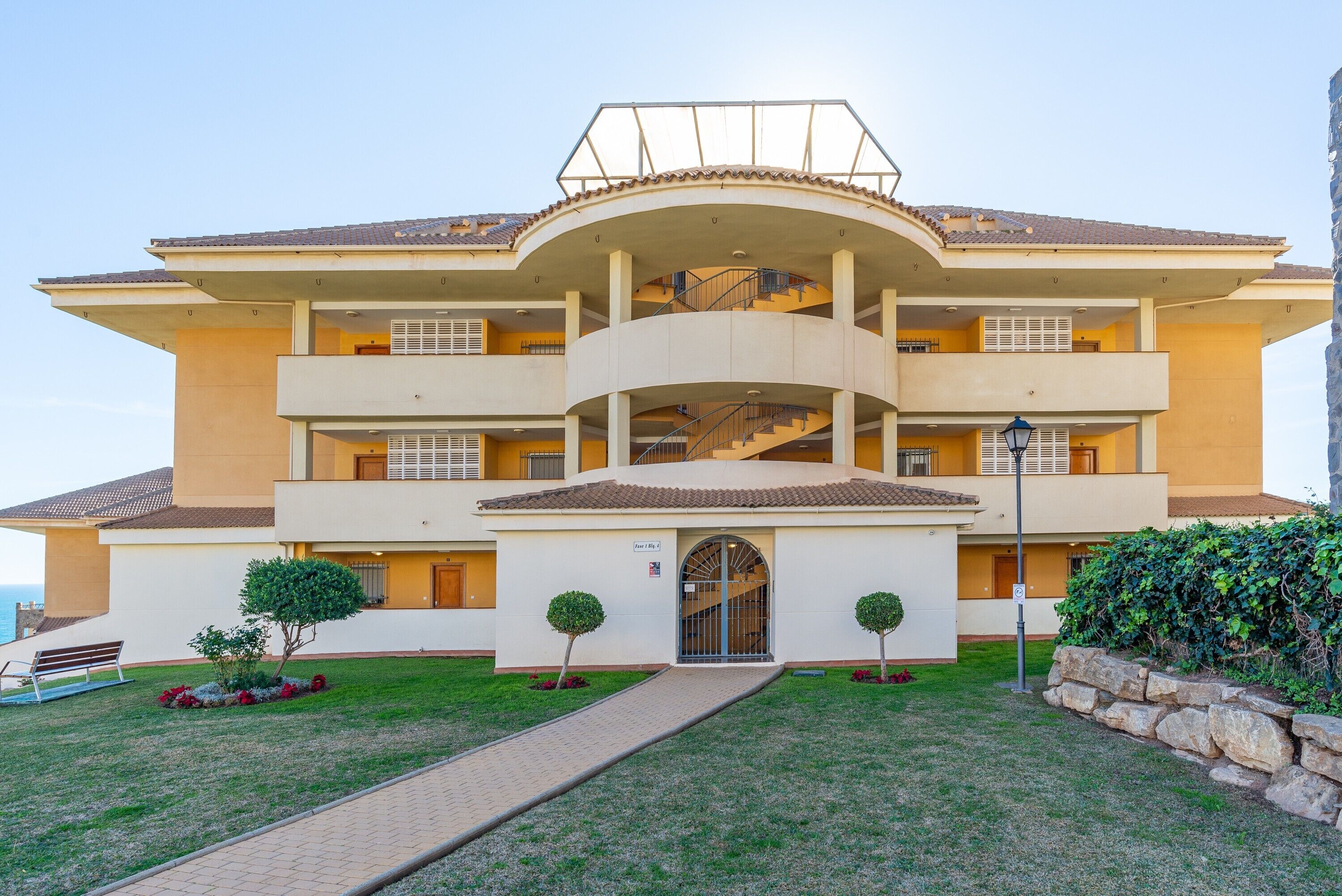 A multi-story building with a central courtyard, balconies, and a gated entrance.