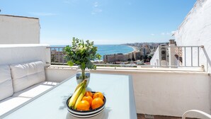 Een balkon met een tafel, een fruitschaal en een bloempot.