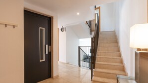 A modern interior with a dark door, a staircase, and a glass table.