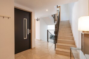 Un interior moderno con una puerta oscura, una escalera y una mesa de vidrio.