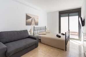 Un dormitorio con cama, sofá, un cuadro y televisor.