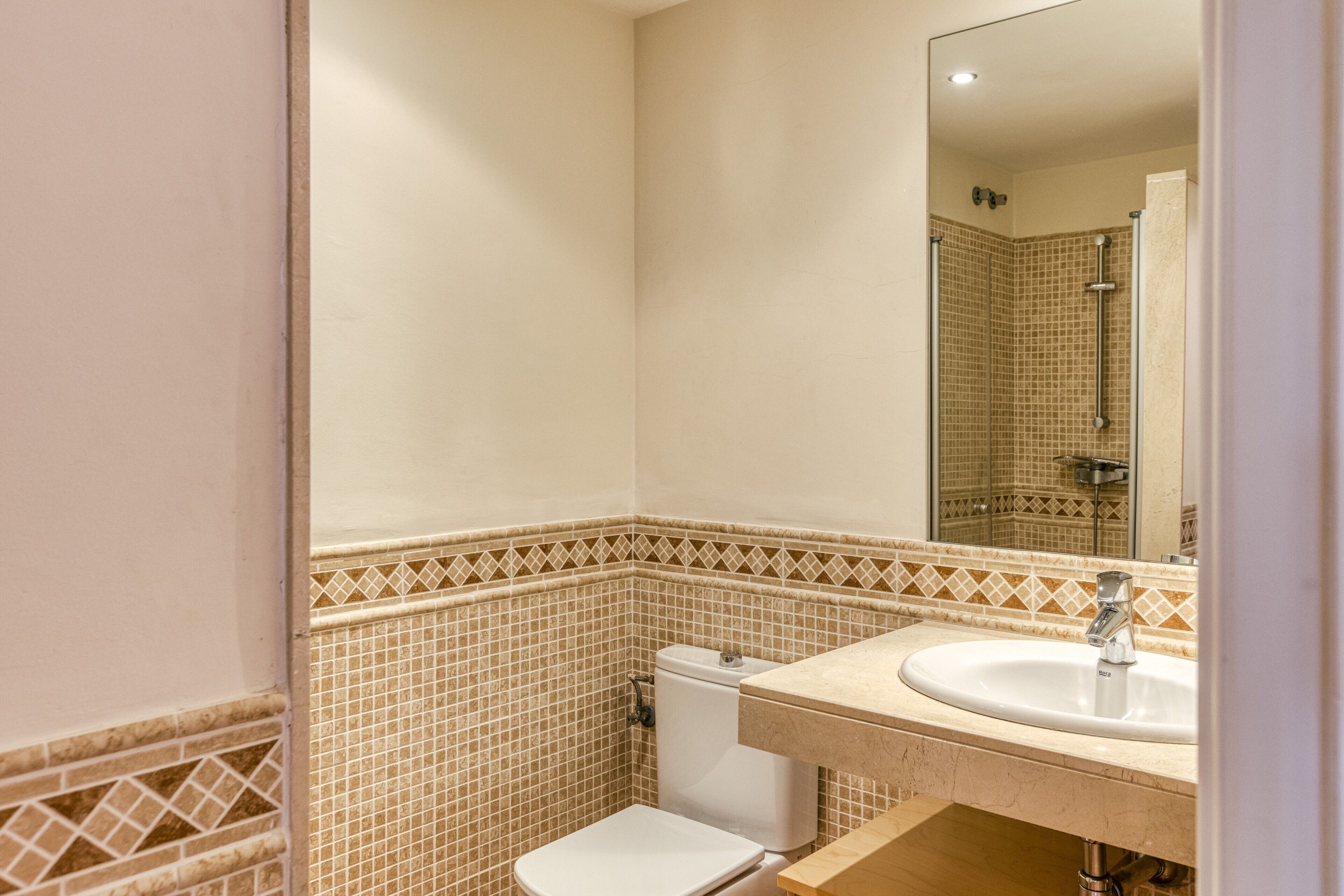 Een badkamer met toilet, wastafel en spiegel.