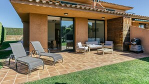 Ein modernes Haus mit einer Terrasse, Sitzgelegenheiten im Freien und einem Grillbereich.