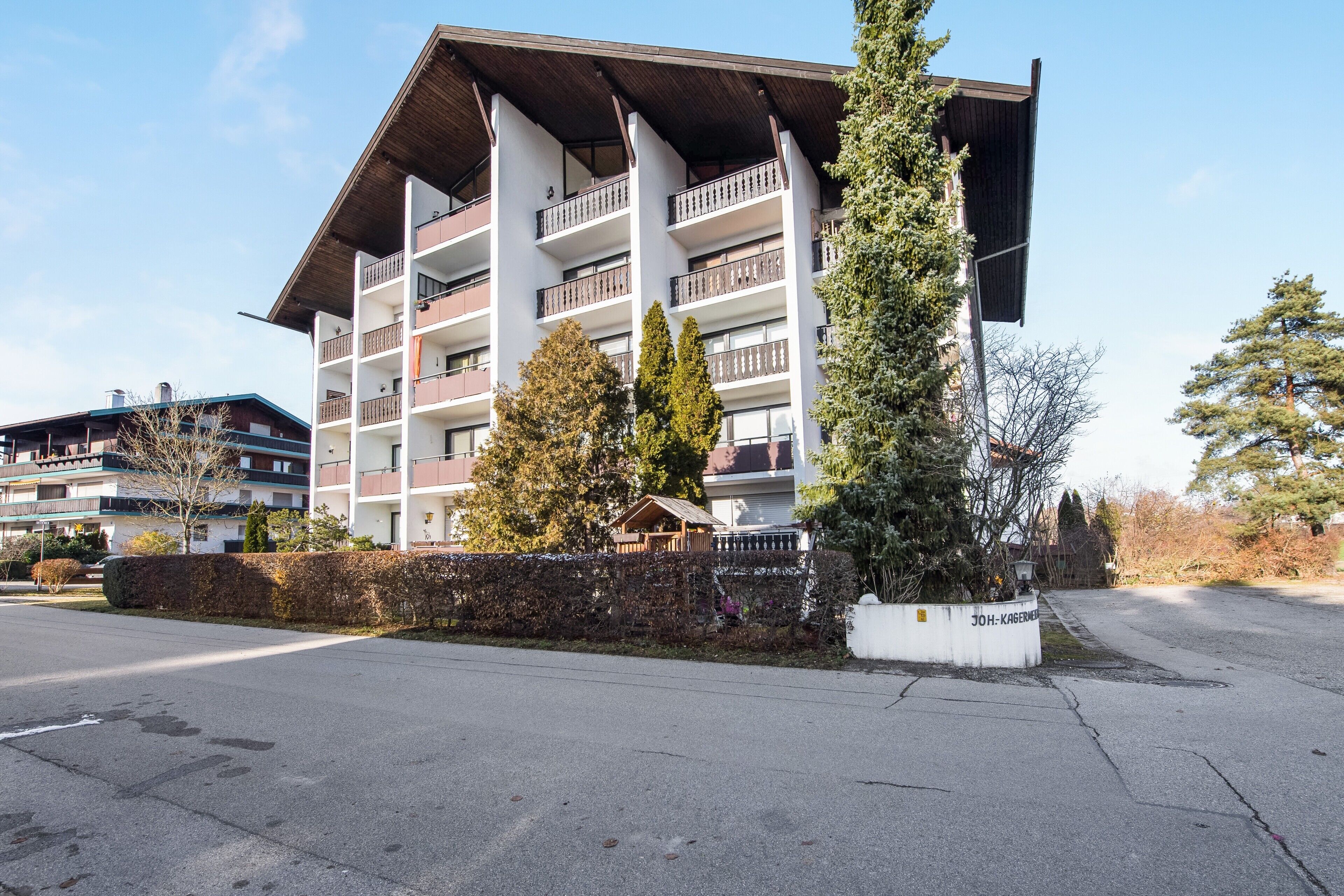 Un hôtel à plusieurs étages doté de balcons, d’une entrée couverte et d’un jardin bien entretenu.
