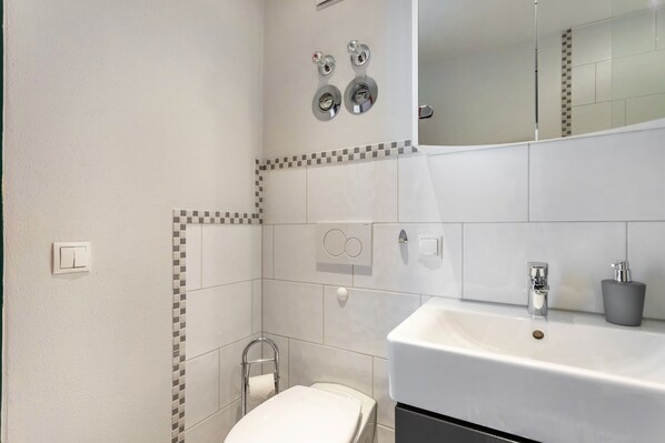 A modern bathroom with a toilet, sink, and mirror.