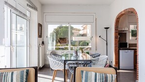 Un comedor con mesa de vidrio, sillas de mimbre y vistas al exterior.