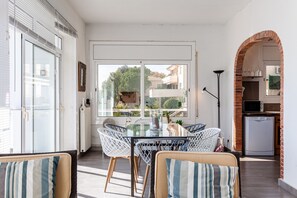 A dining area with a glass table, wicker chairs, and a view of the outdoors.