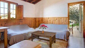Una habitación acogedora con paredes de madera, un sofá, una mesa con una planta en maceta y una puerta que da al exterior.