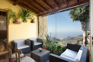A balcony with wicker furniture, potted plants, and a view of the landscape. - Vacation Home Mirador de Domingo with Mountain View, Sea View, Terraces & Garden (Gáldar)