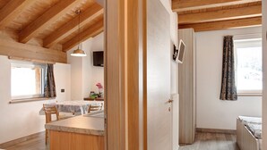 Un intérieur en bois comprenant un coin cuisine, une table à manger et un lit.