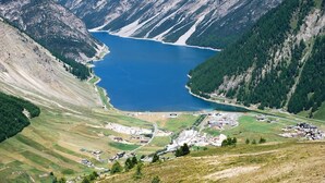 Un paysage montagneux avec un lac, des champs en terrasses et des bâtiments dispersés.