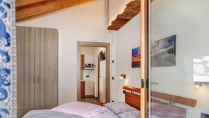 Une chambre à coucher comprenant un lit, une armoire, une porte donnant sur une salle de bain et un tableau accroché au mur.