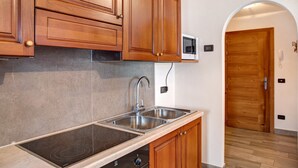 Une cuisine dotée de meubles en bois, d’un évier en acier inoxydable et d’une plaque de cuisson électrique intégrée.