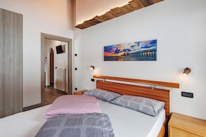 Une chambre à coucher avec une tête de lit en bois, un tableau représentant une jetée et une table de chevet avec une lampe.