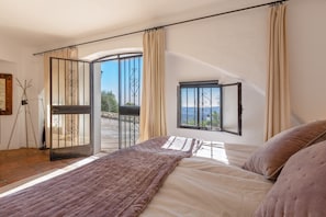 Een slaapkamer met een bed, gordijnen, een raam en een deur.