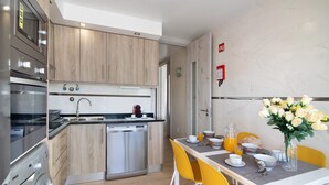 Eine moderne Küche mit Holzschränken, Edelstahlgeräten und einem Essbereich mit gelben Stühlen und einem für das Frühstück gedeckten Tisch.