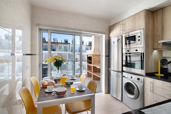 Une cuisine moderne avec un coin repas, un lave-linge et une vue sur la ville.