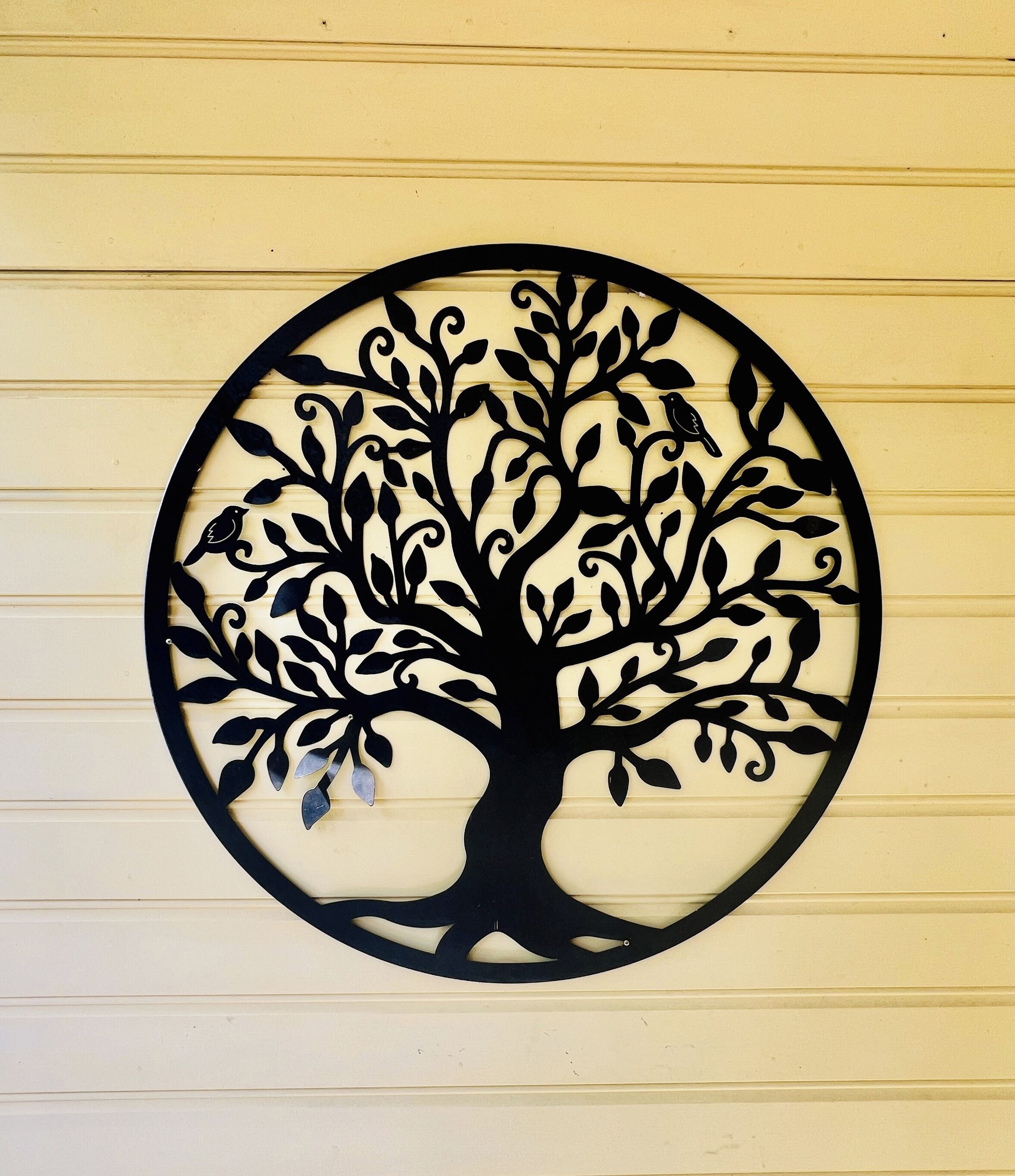 A circular metal wall art with a tree design.