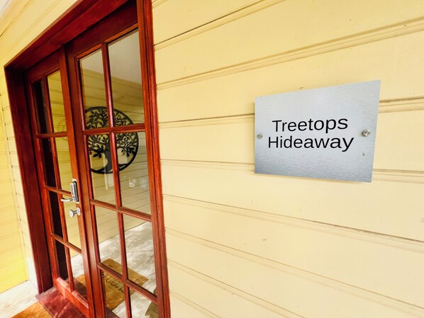 Une porte en bois avec un panneau de verre et une enseigne indiquant « Treetops Hideaway ».