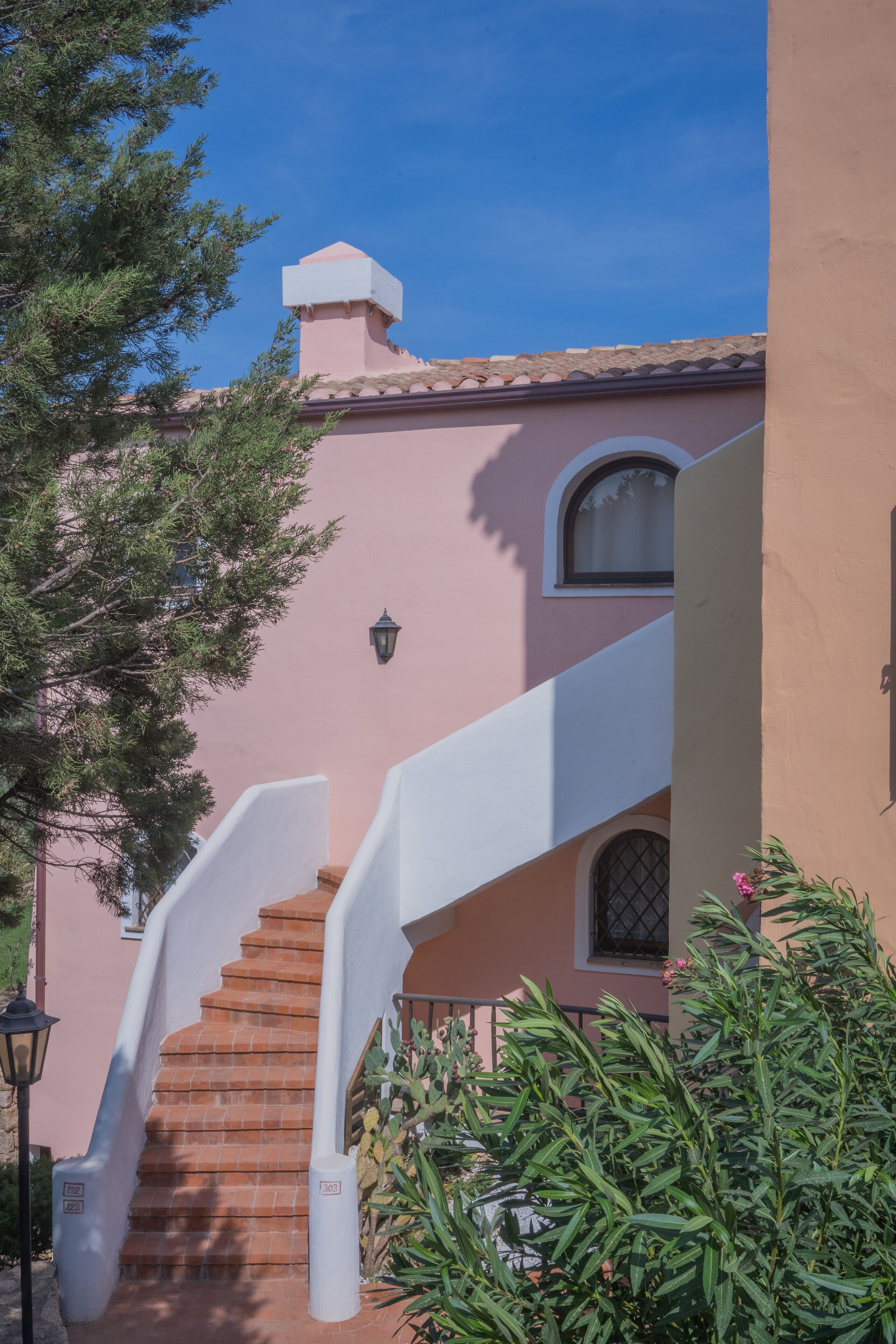 A staircase leading to a building with a pink facade and a white railing.