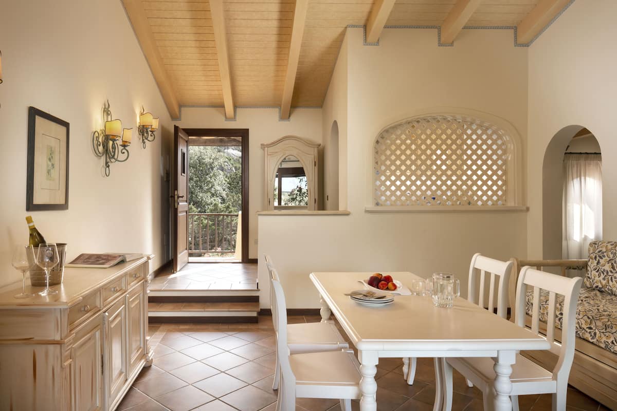 Un comedor con una mesa y sillas blancas, vistas al exterior y una pared decorativa con diseño de celosía.