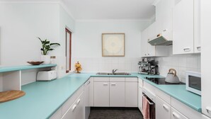 Una cucina moderna con mobili bianchi, un piano di lavoro verde acqua, una macchina per caffè e un bollitore.