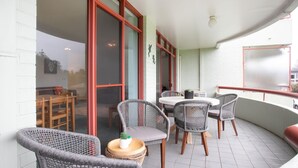 Un balcone con sedie in vimini, un tavolino rotondo e una pianta in vaso.