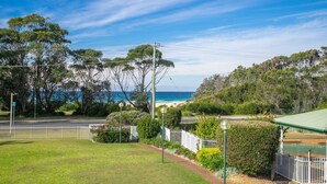 Un immobile sul lungomare con vista sull'oceano, un giardino recintato e una strada con linee elettriche.