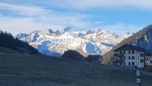 Ein Bergdorf mit Chalets, einer Seilbahn und schneebedeckten Berggipfeln im Hintergrund.