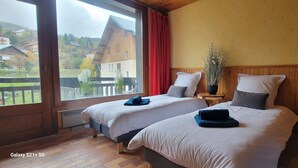 Ein Hotelzimmer mit zwei Betten, einem großen Fenster, einer Zimmerpflanze und Blick nach draußen.