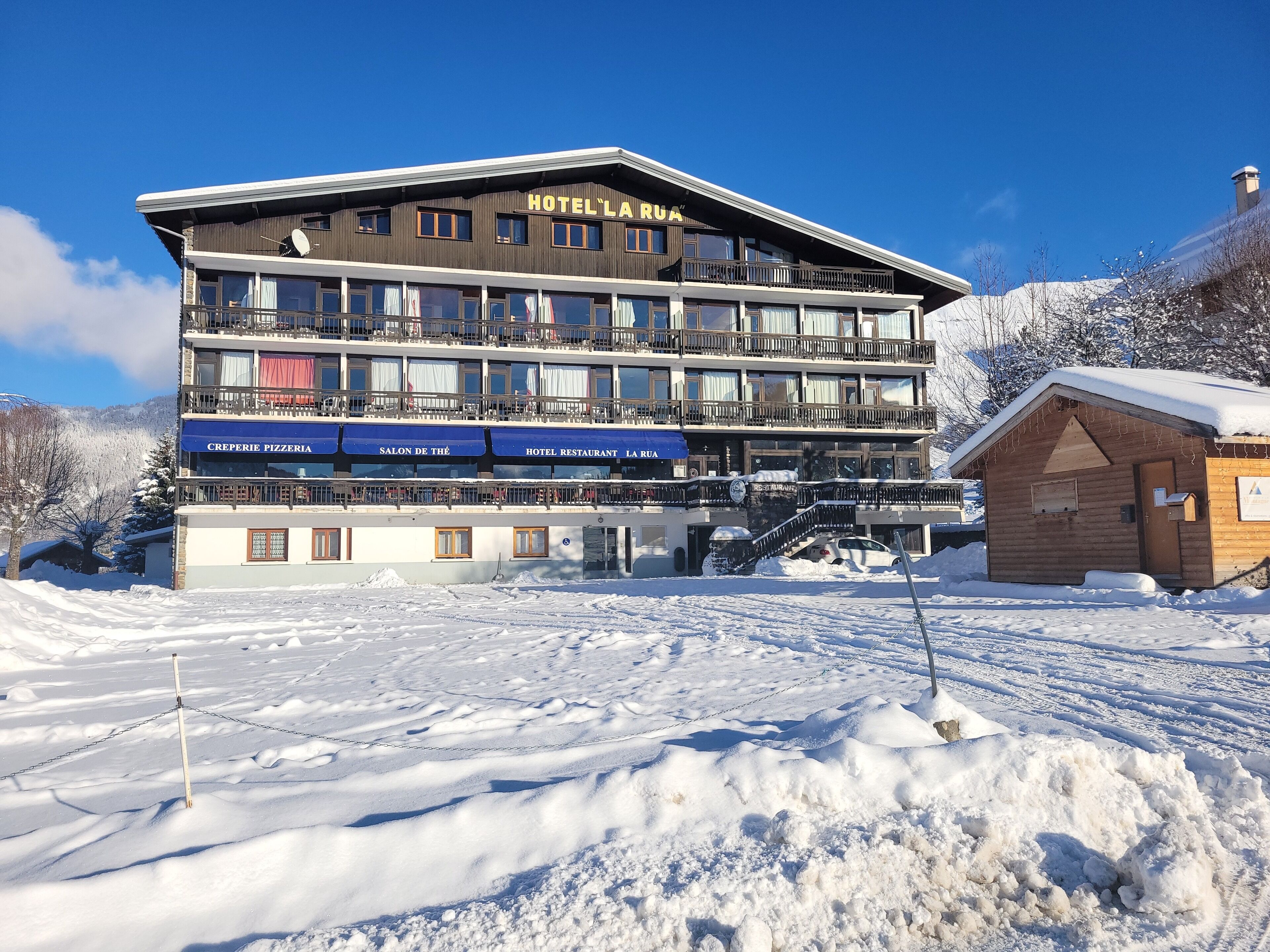A multi-story hotel with balconies and a restaurant on the ground floor.